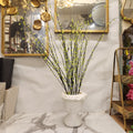 artificial Forsythia inside a white ceramic hourglass vase