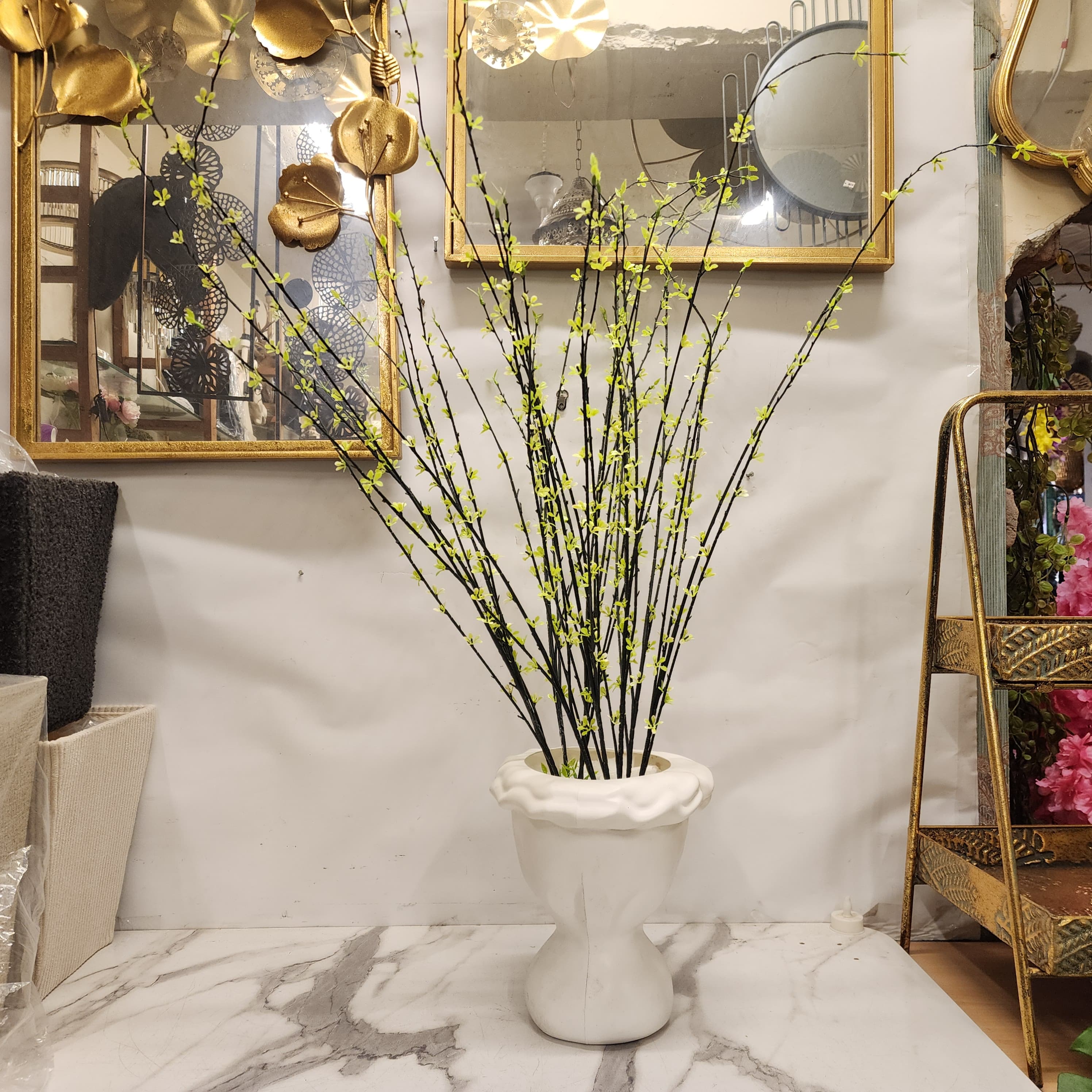artificial Forsythia inside a white ceramic hourglass vase
