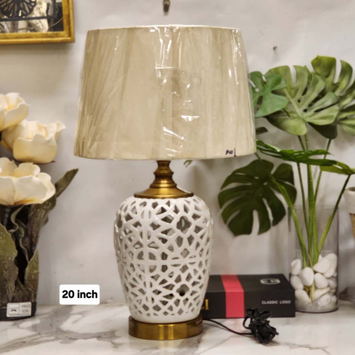 reticulated white ceramic table lamp with a brass base and a tapered fabric drum shade.
