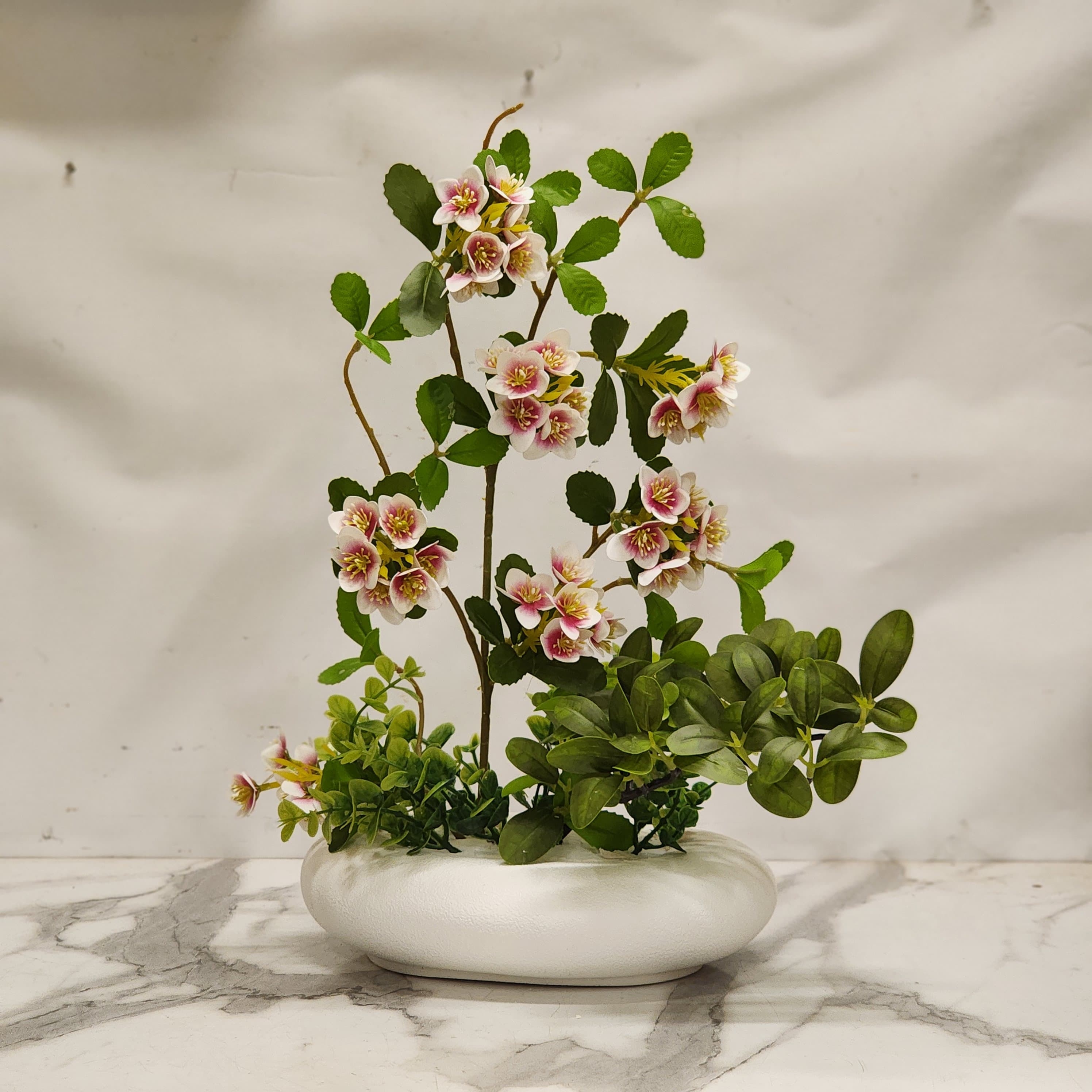 white cherry blossoms in a low-profile white oval ceramic pot